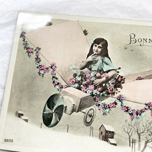 1910s - Vintage French New Year Postcard - Whimsical Little Girl Flying Flower-Adorned Biplane - Unique Early Aviation Themed Greeting Card
