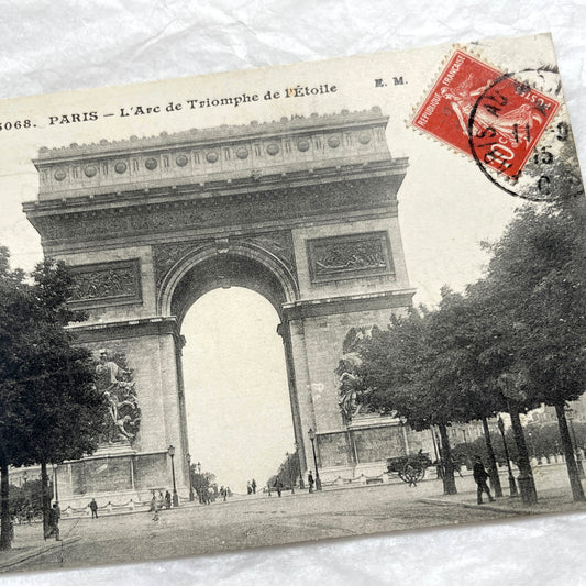 1900s postcard of Paris Arc de Triomphe with horse carriages and pedestrians on a tree-lined street.