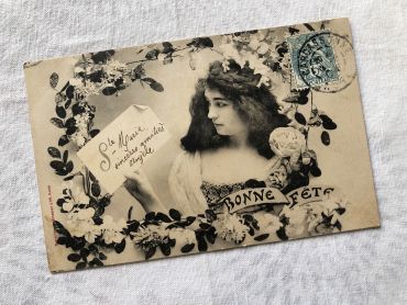 French postcard representing a young woman surrounded by flowers with the legend "Bonne fte" from 1900s