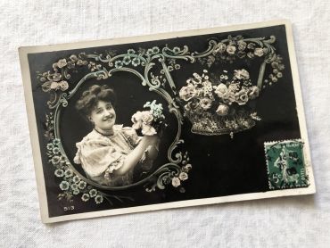 French postcard representing a young woman surrounded by flowers from 1900s