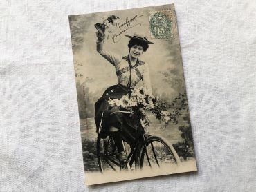 French postcard representing a young woman on a bicycle from 1900s