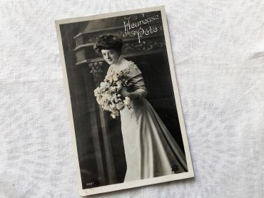 Vintage Belgian postcard representing a young woman with a bouquet of flowers