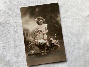 French vintage postcard representing a little girl with flowers from 1910s