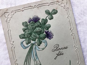 Vintage Swiss embossed postcard with a small bouquet of four-leaf clovers from 1920s.