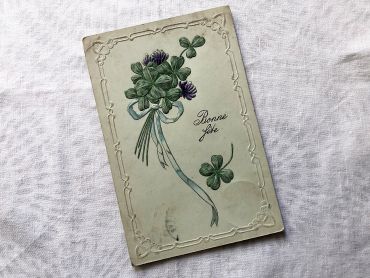 Vintage Swiss embossed postcard with a small bouquet of four-leaf clovers from 1920s.