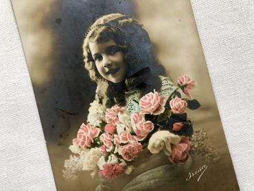 Vintage Belgian postcard with young girl with a bouquet of flowers from 1910