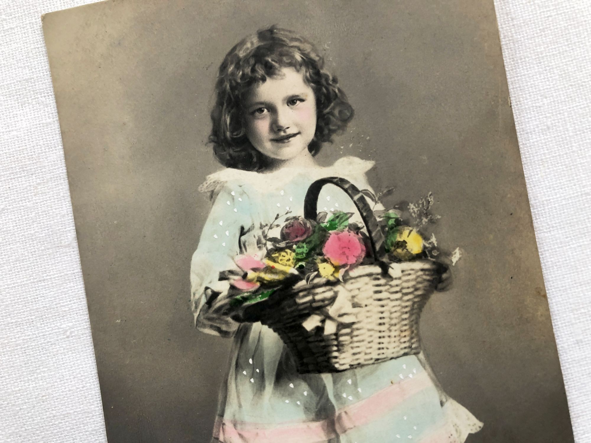 Vintage French postcard with a young child with a basket of flowers from 1900s