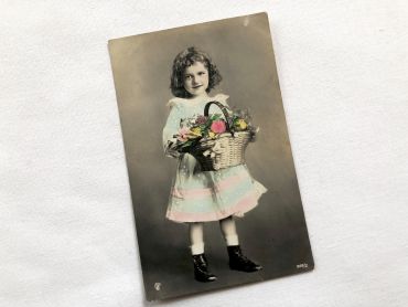 Vintage French postcard with a young child with a basket of flowers from 1900s
