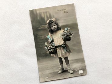 Vintage Belgian postcard with a young child with two baskets of flowers from 1910s