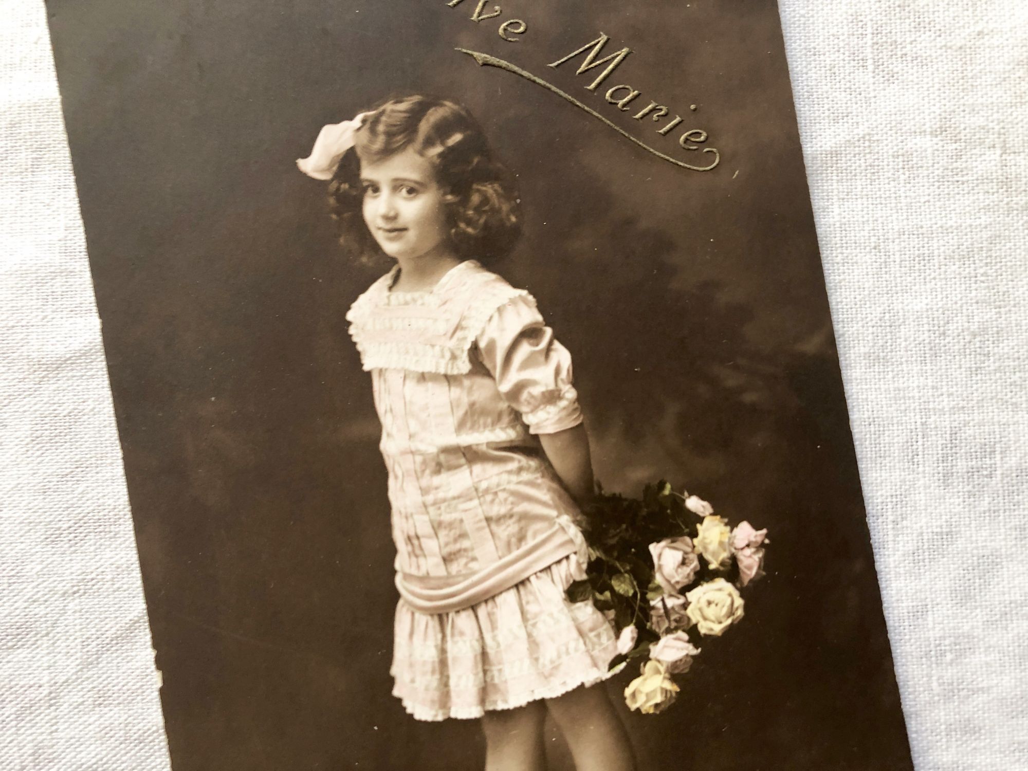 Vintage Belgian postcard with young girl with a bouquet of flowers