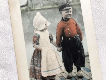 Belgian postcard of a little girl holding a little boy by the side of a canal fro 1910s