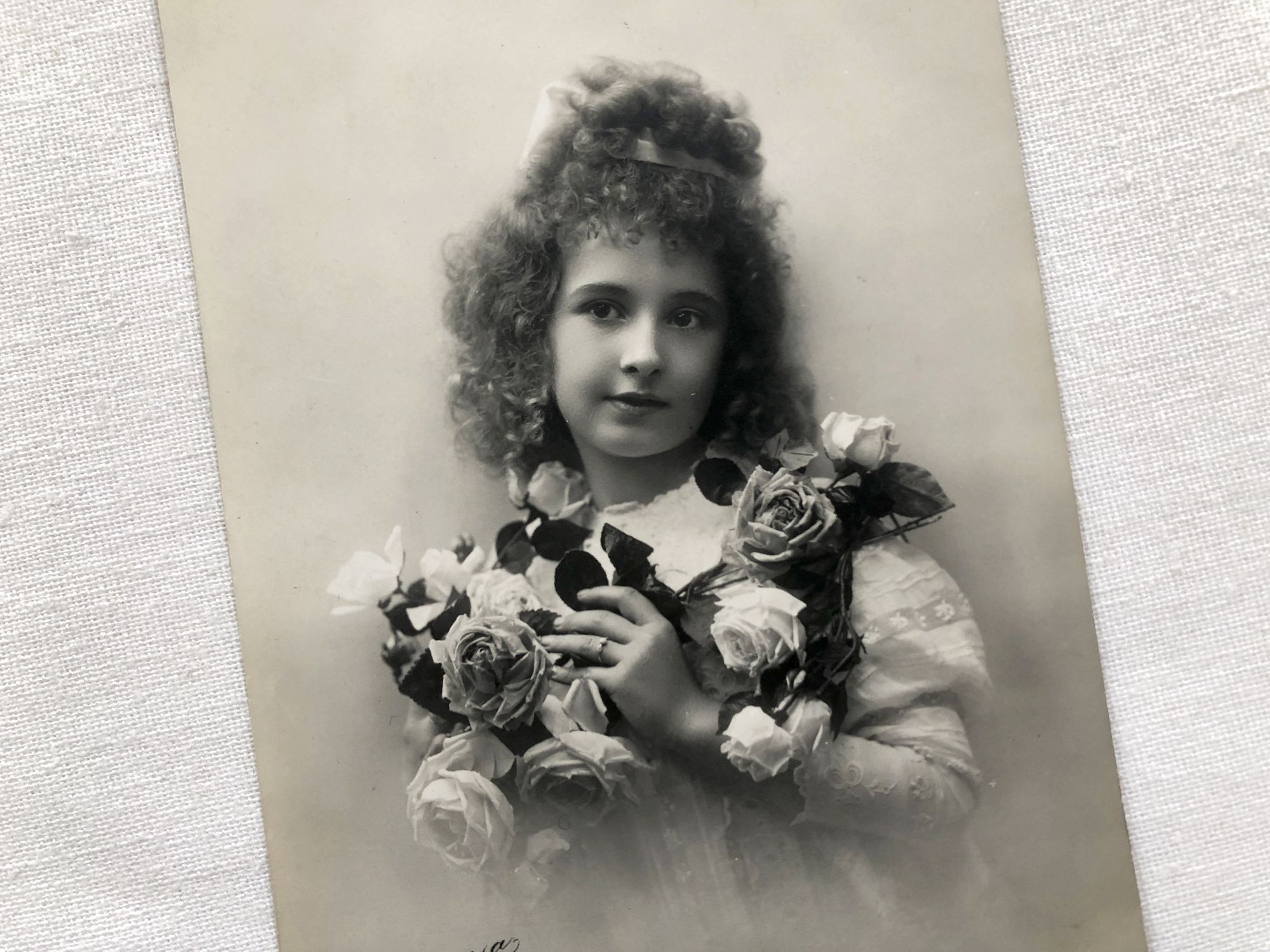 French postcard with a daughter carrying a bunch of roses from 1910s