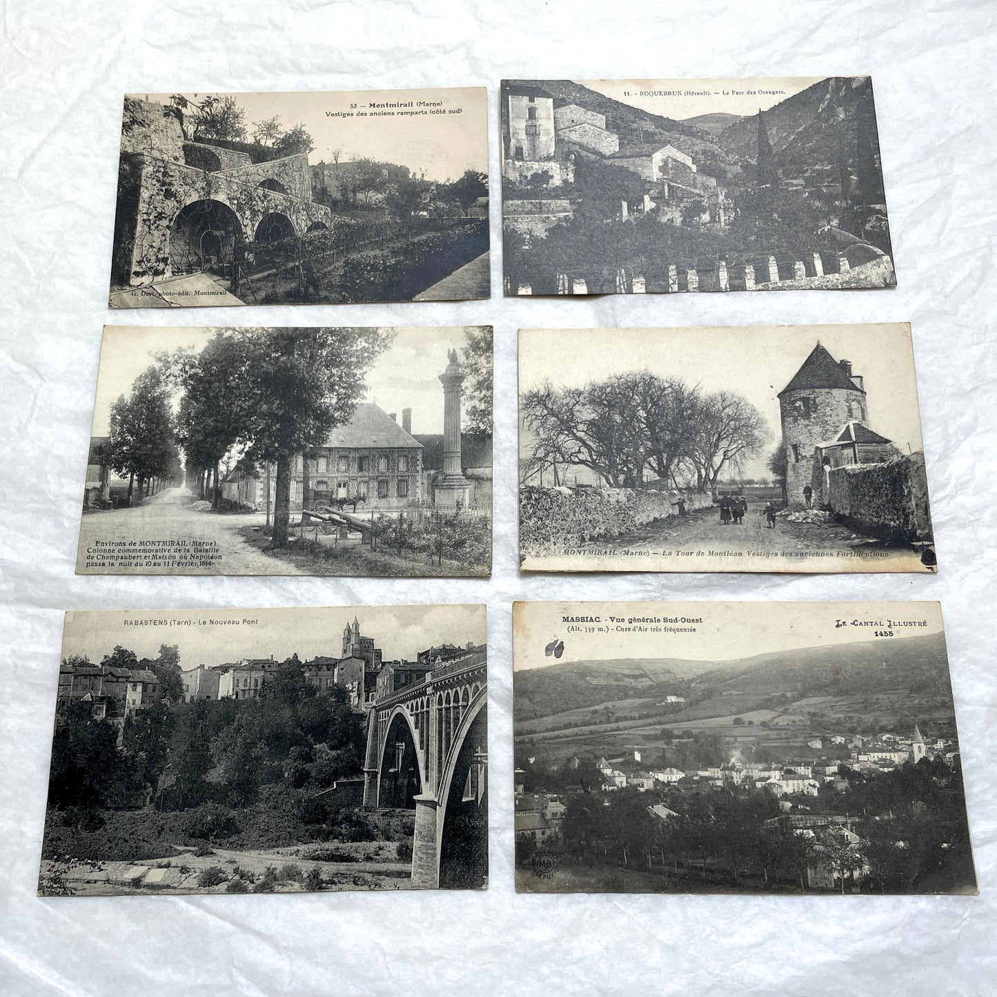 Lot of 1910s French postcards showing historic village scenes, old ramparts, a bridge, and a tower in France.