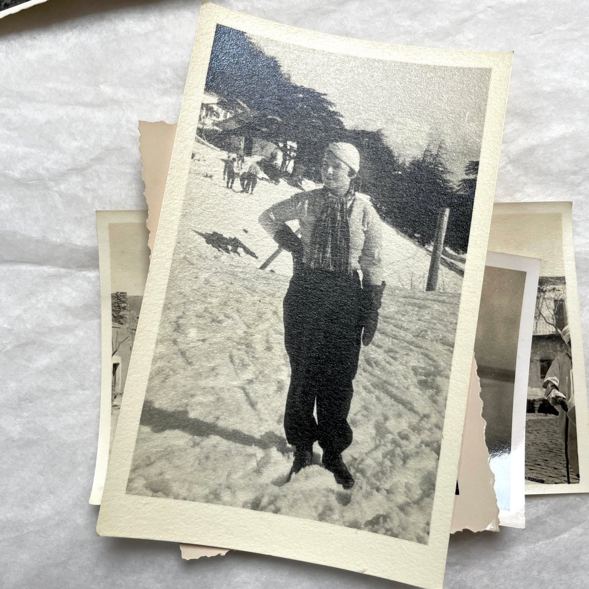 Lot of 1940s vintage photographs showing people skiing, a camel rider, an ocean scene with a military man, and a dog.