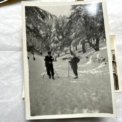 Lot of 1940s vintage photographs showing people skiing, a camel rider, an ocean scene with a military man, and a dog.