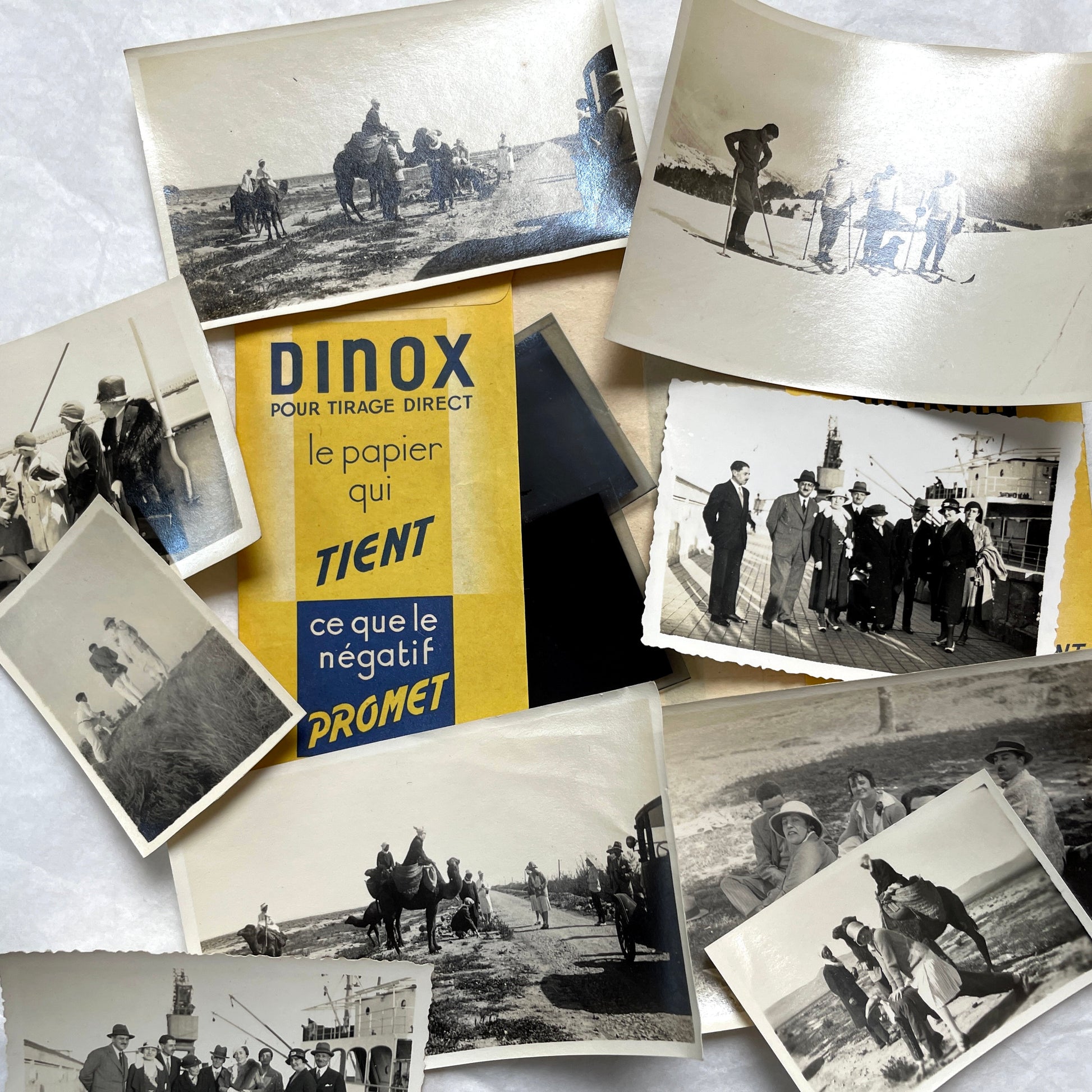 1920s vintage photograph lot showing people skiing in mountains, riding camels in the desert, and gathered on a ship deck.