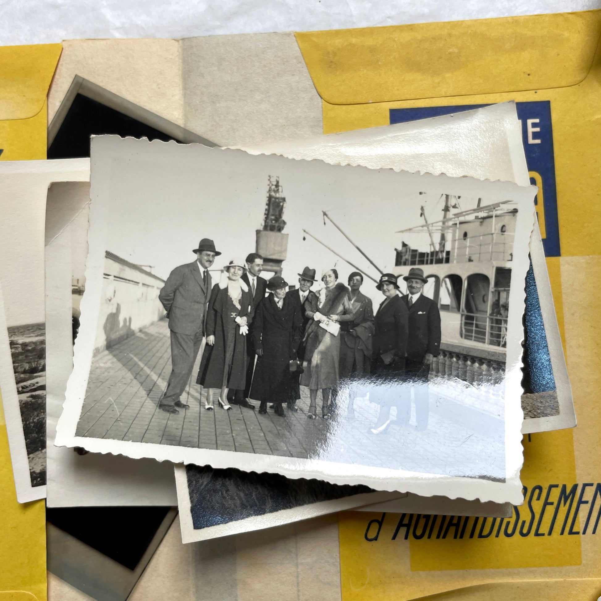 1920s vintage photograph lot showing people skiing in mountains, riding camels in the desert, and gathered on a ship deck.
