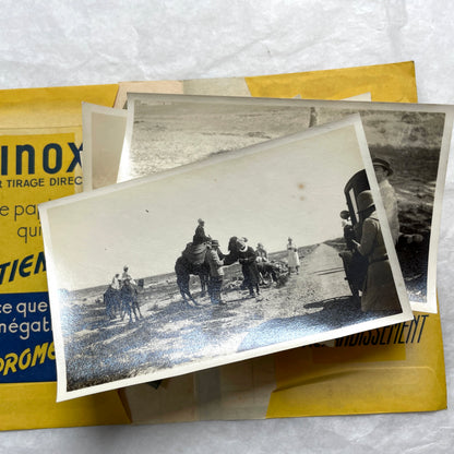 1920s vintage photograph lot showing people skiing in mountains, riding camels in the desert, and gathered on a ship deck.
