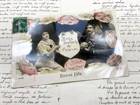 1910s - Hand-Colored French Postcard “Bonne Fête” – Early 20th Century Floral Border with Seated Couple and Festive Wishes