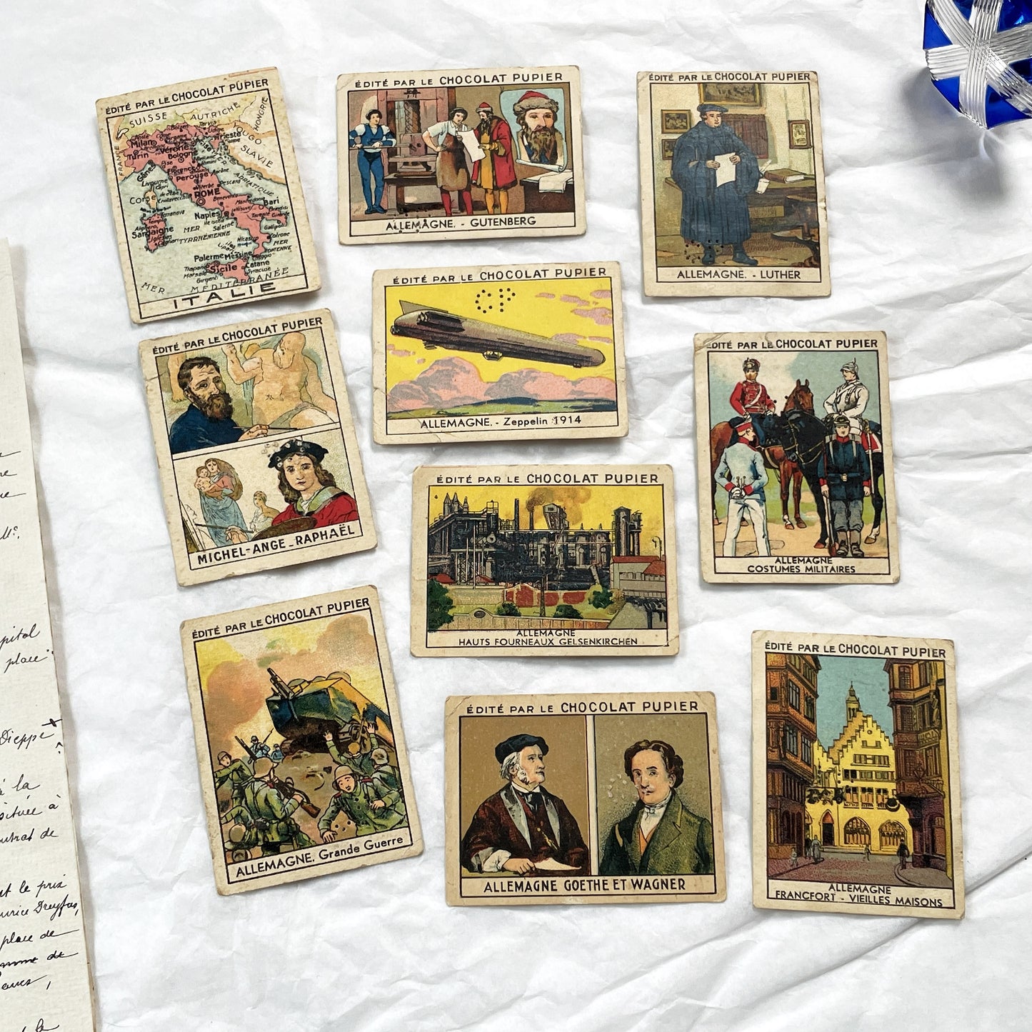 1910s - 10 Pupier Chocolate Trade Cards - Historical Figures and Cultural Heritage - Germany, Italy, Zeppelin, WWI, Art, Military, Cities