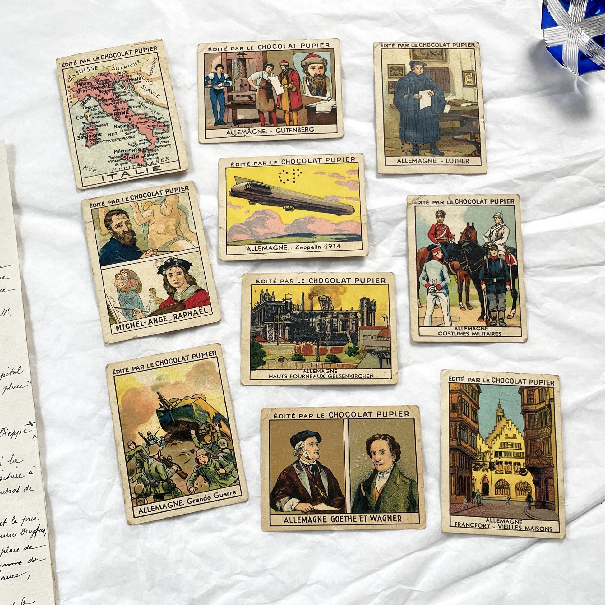 1910s - 10 Pupier Chocolate Trade Cards - Historical Figures and Cultural Heritage - Germany, Italy, Zeppelin, WWI, Art, Military, Cities