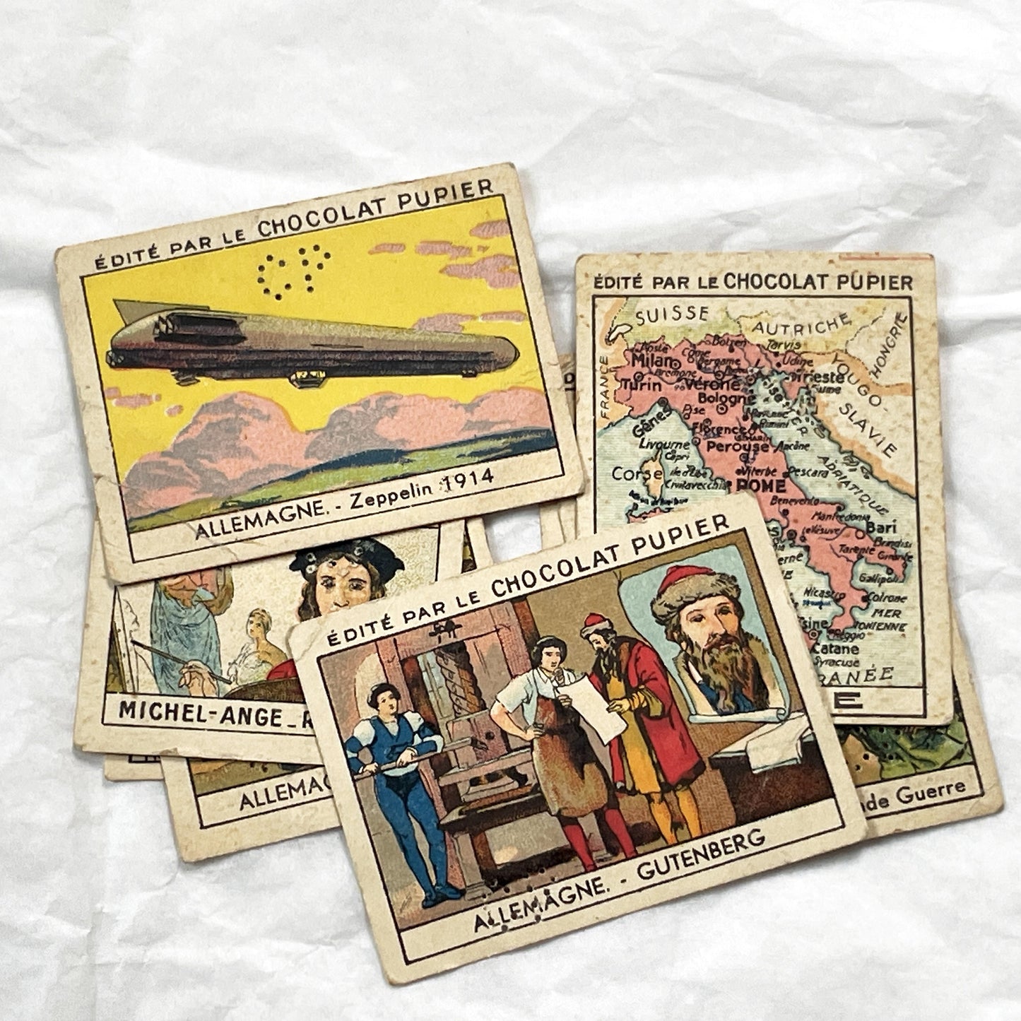 1910s - 10 Pupier Chocolate Trade Cards - Historical Figures and Cultural Heritage - Germany, Italy, Zeppelin, WWI, Art, Military, Cities