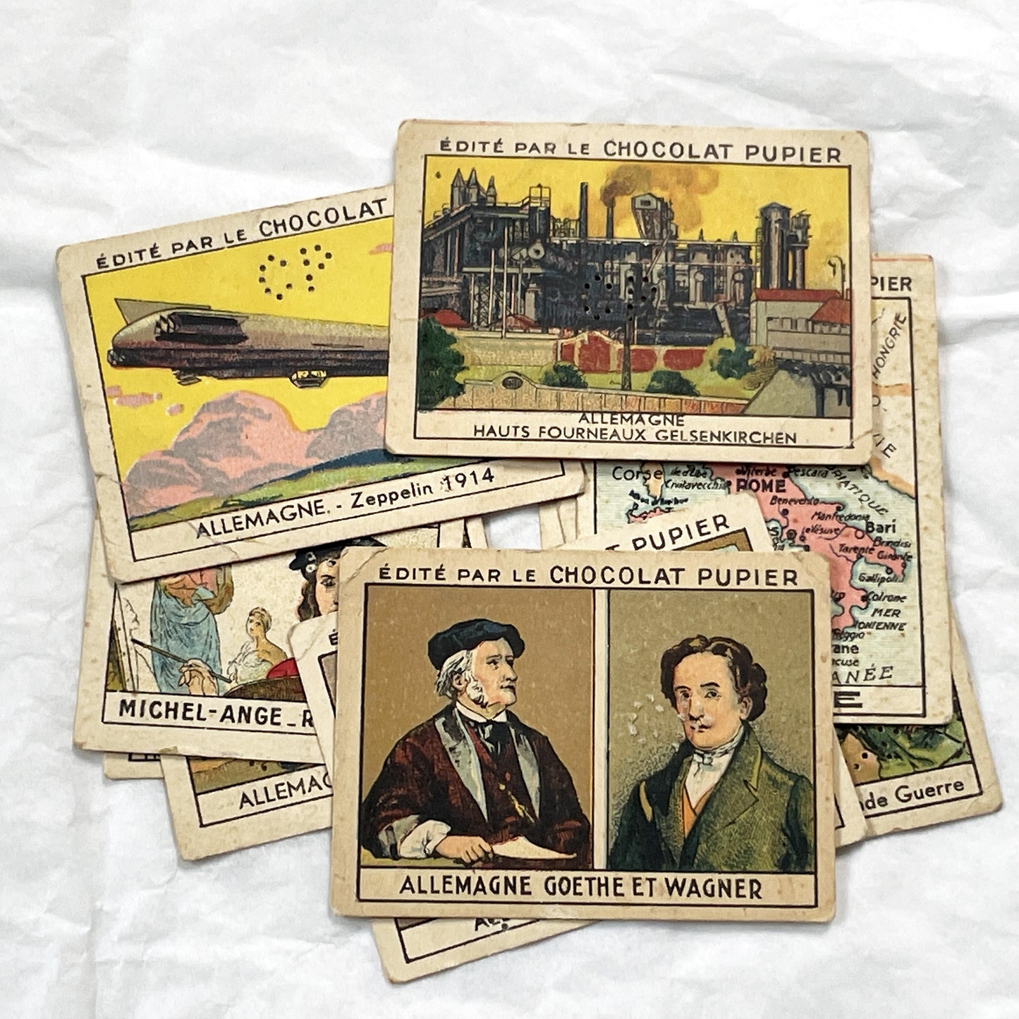 1910s - 10 Pupier Chocolate Trade Cards - Historical Figures and Cultural Heritage - Germany, Italy, Zeppelin, WWI, Art, Military, Cities