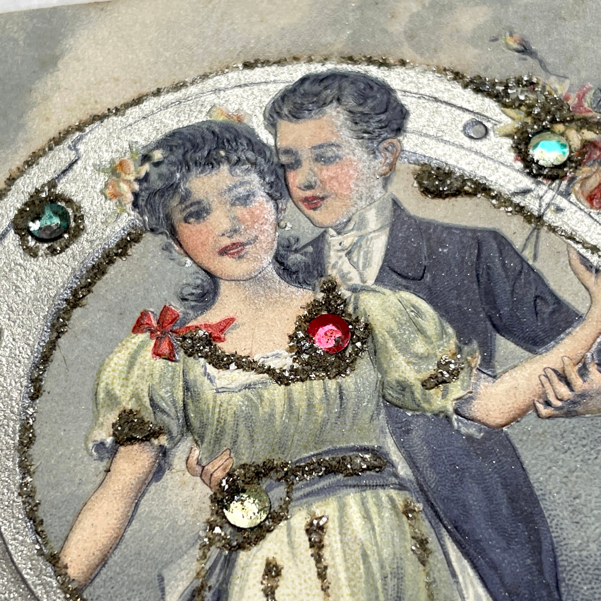 1900s French postcard with a couple holding a glitter horseshoe, adorned with small gems.
