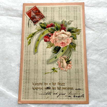 1900s French postcard with embossed pink roses and a green lucky horseshoe on a plaid background.