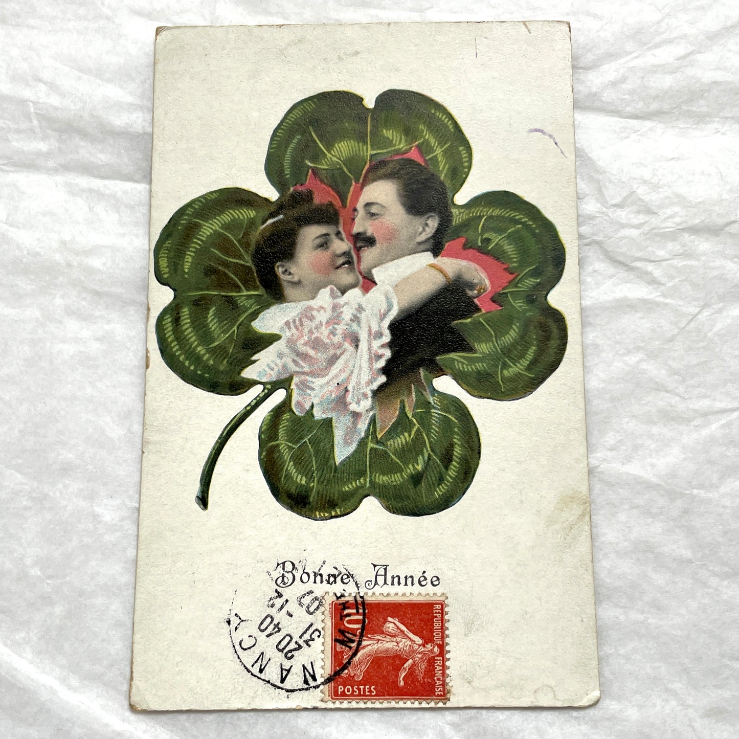 1900s postcard with a romantic couple embracing inside a green four-leaf clover, French New Year greeting.