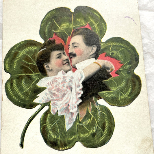 1900s postcard with a romantic couple embracing inside a green four-leaf clover, French New Year greeting.