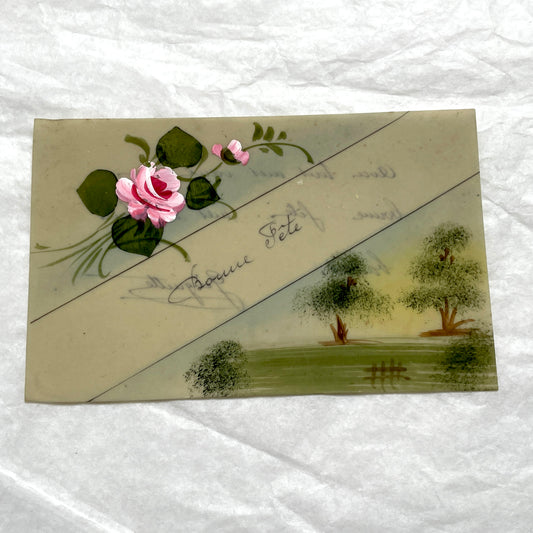 1910s French greeting card with hand-painted pink rose, green leaves, and rustic landscape scene.
