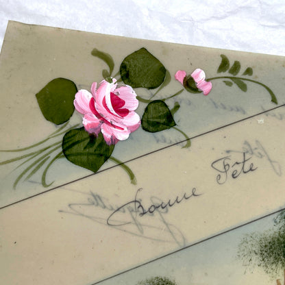 1910s French greeting card with hand-painted pink rose, green leaves, and rustic landscape scene.