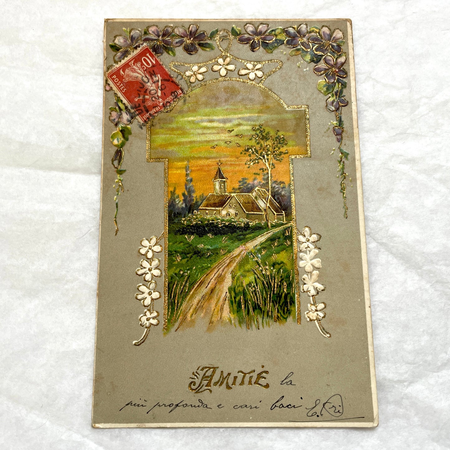 1900s French postcard featuring a gilded church landscape, floral border, and an antique 10c Postes stamp.