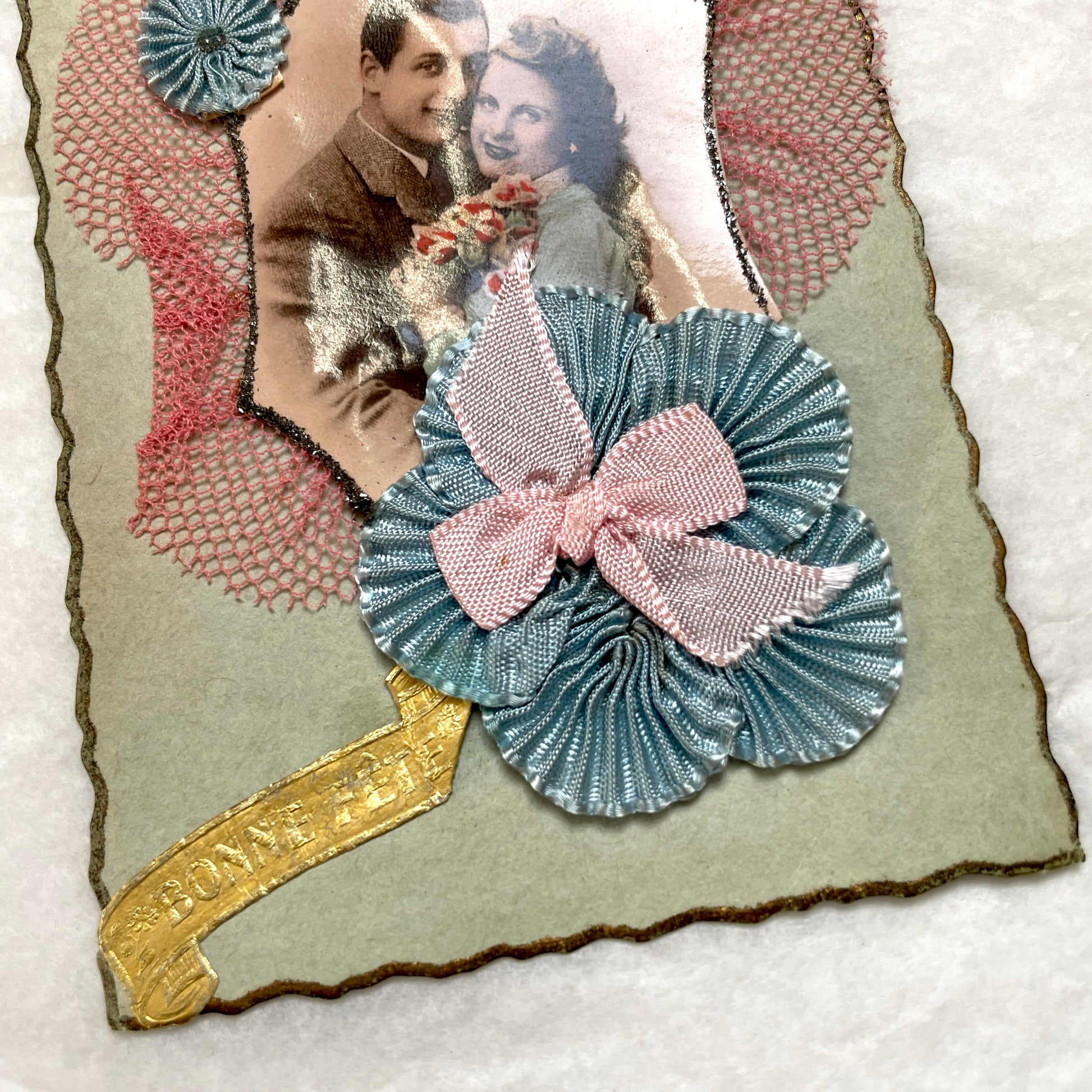 1940s French greeting card featuring a romantic couple's photo, blue pleated ribbon, and 'Bonne Fête' banner.