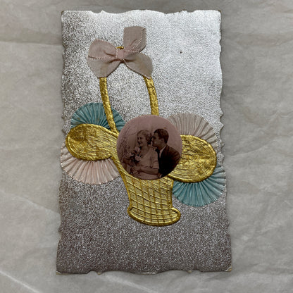 1930s vintage decorative card with a sepia wedding couple photo, golden embossed basket, and pastel ribbons on silver.