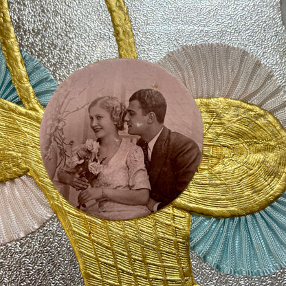 1930s vintage decorative card with a sepia wedding couple photo, golden embossed basket, and pastel ribbons on silver.