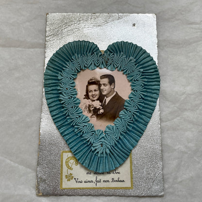 1940s French postcard with a sepia photo of a couple, framed by a blue ribbon heart and romantic French text.