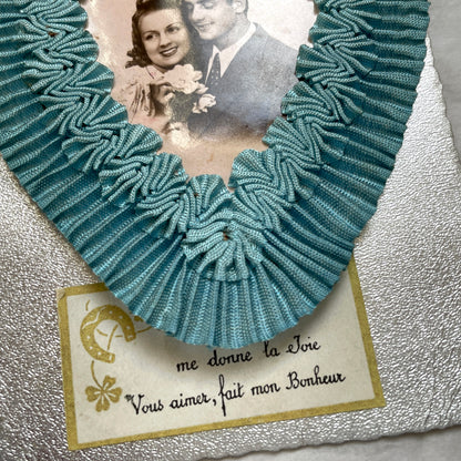 1940s French postcard with a sepia photo of a couple, framed by a blue ribbon heart and romantic French text.