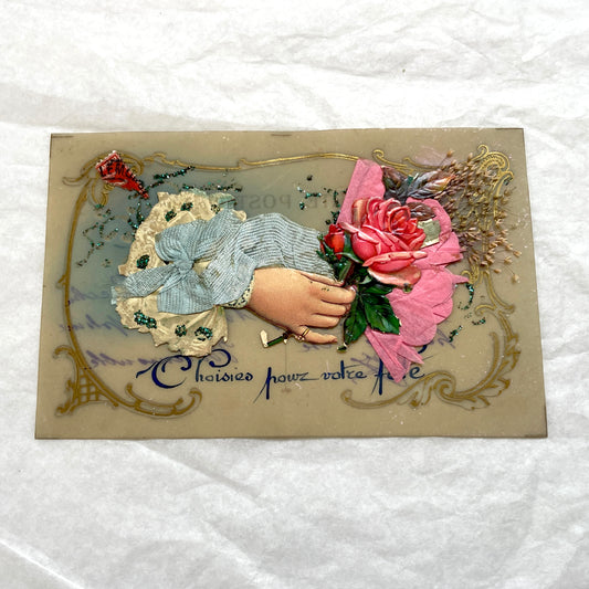 1900s French postcard with embossed hand holding pink roses, green glitter, and ornate gold frame.