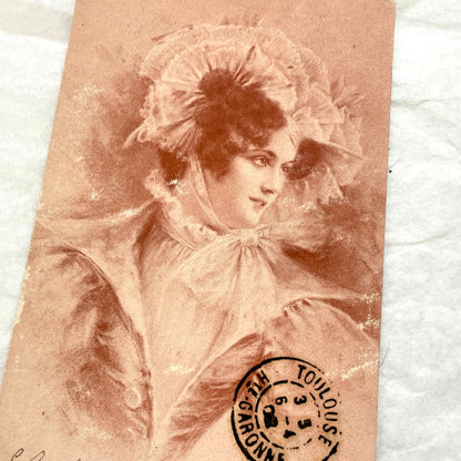 1900s French postcard with an elegant woman wearing a large, fashionable hat, stamped with a Toulouse postmark.