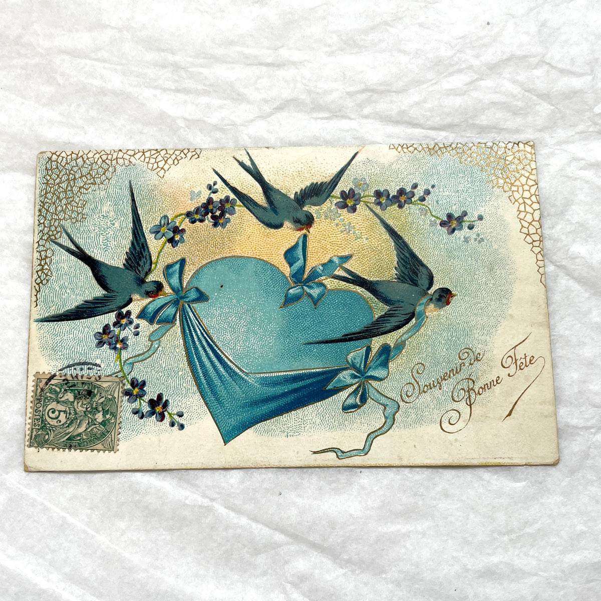 1900s French postcard with three swallows, a blue heart, blue ribbons, and flowers. Vintage ephemera.