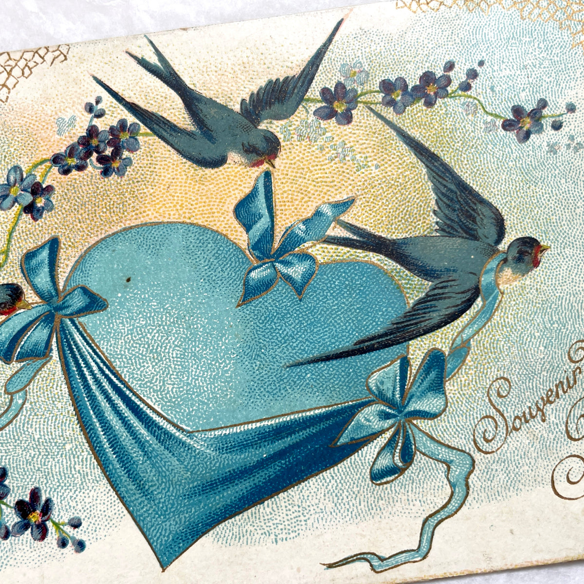 1900s French postcard with three swallows, a blue heart, blue ribbons, and flowers. Vintage ephemera.