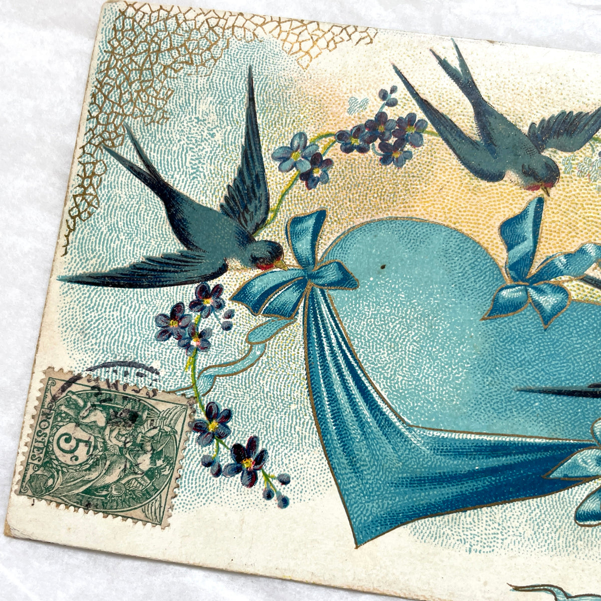 1900s French postcard with three swallows, a blue heart, blue ribbons, and flowers. Vintage ephemera.