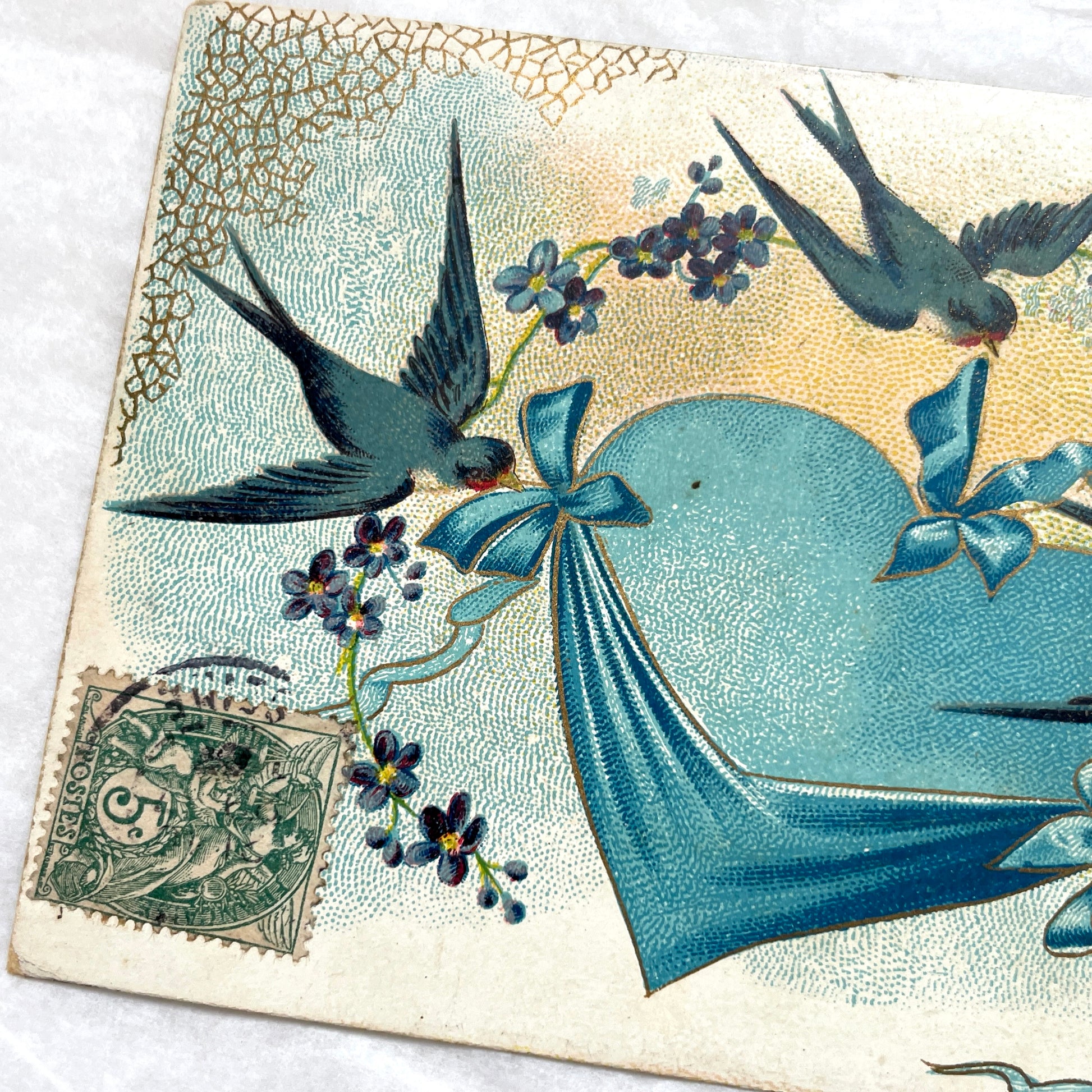 1900s French postcard with three swallows, a blue heart, blue ribbons, and flowers. Vintage ephemera.