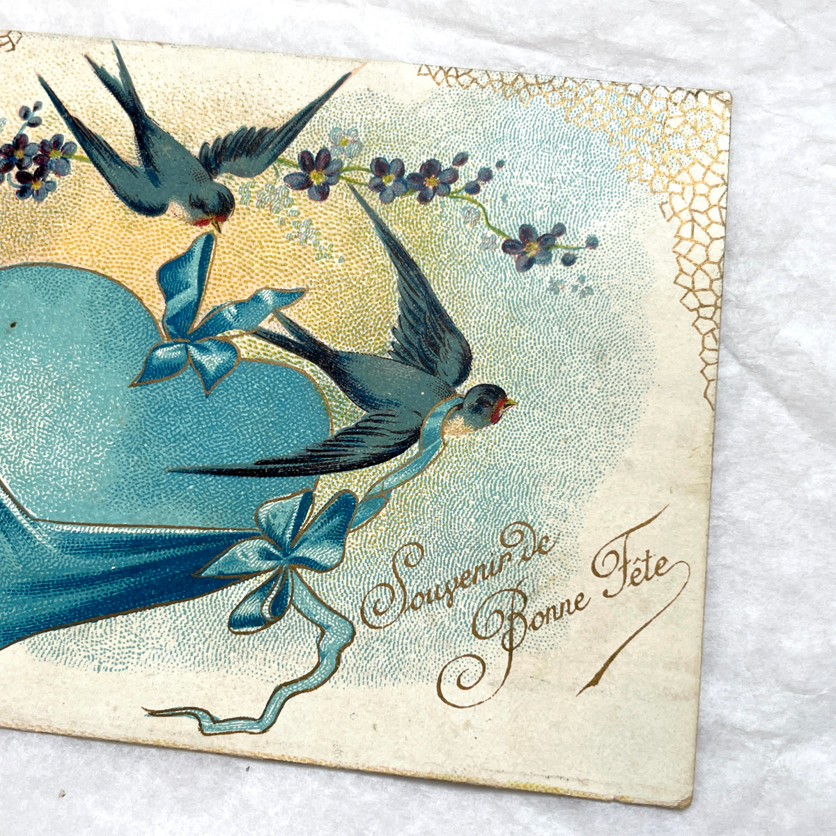 1900s French postcard with three swallows, a blue heart, blue ribbons, and flowers. Vintage ephemera.