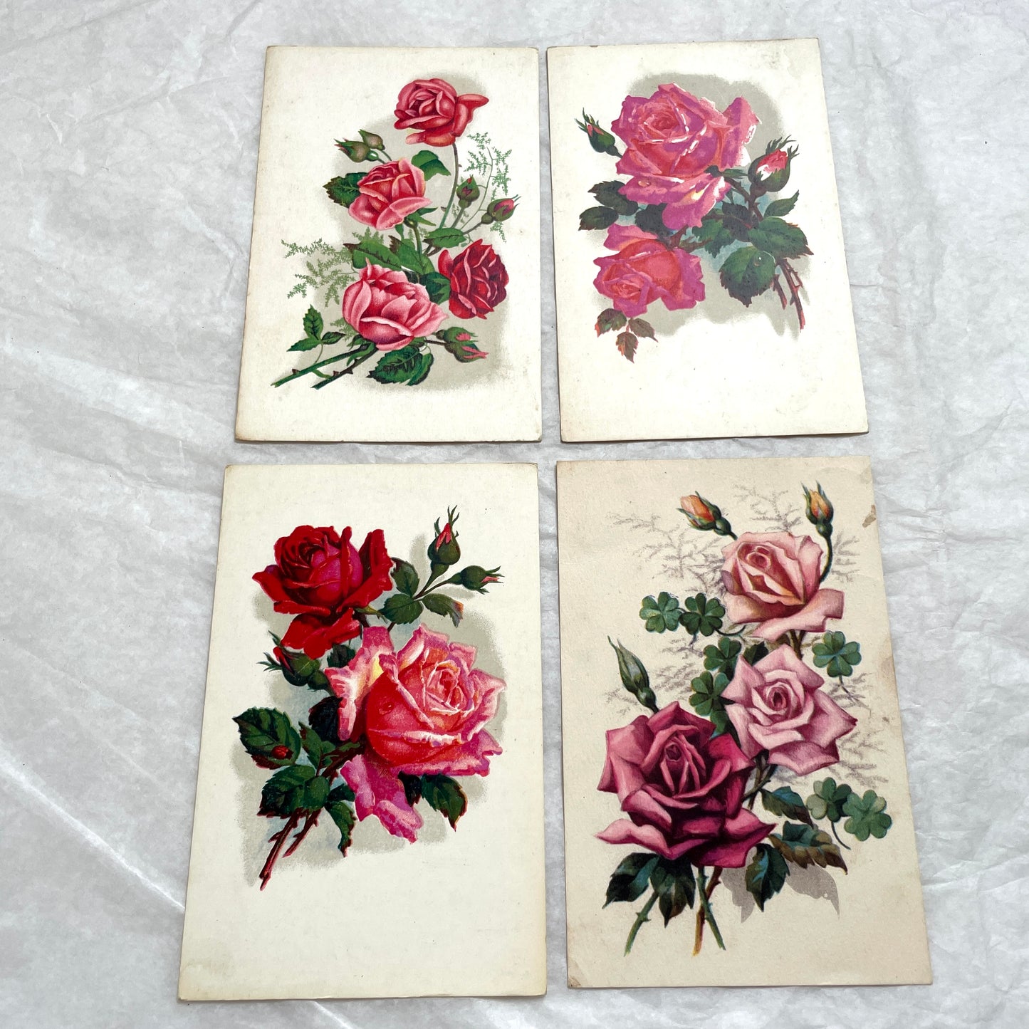 1930s vintage postcard lot featuring four unique illustrations of vibrant red and pink roses with green leaves, floral art.