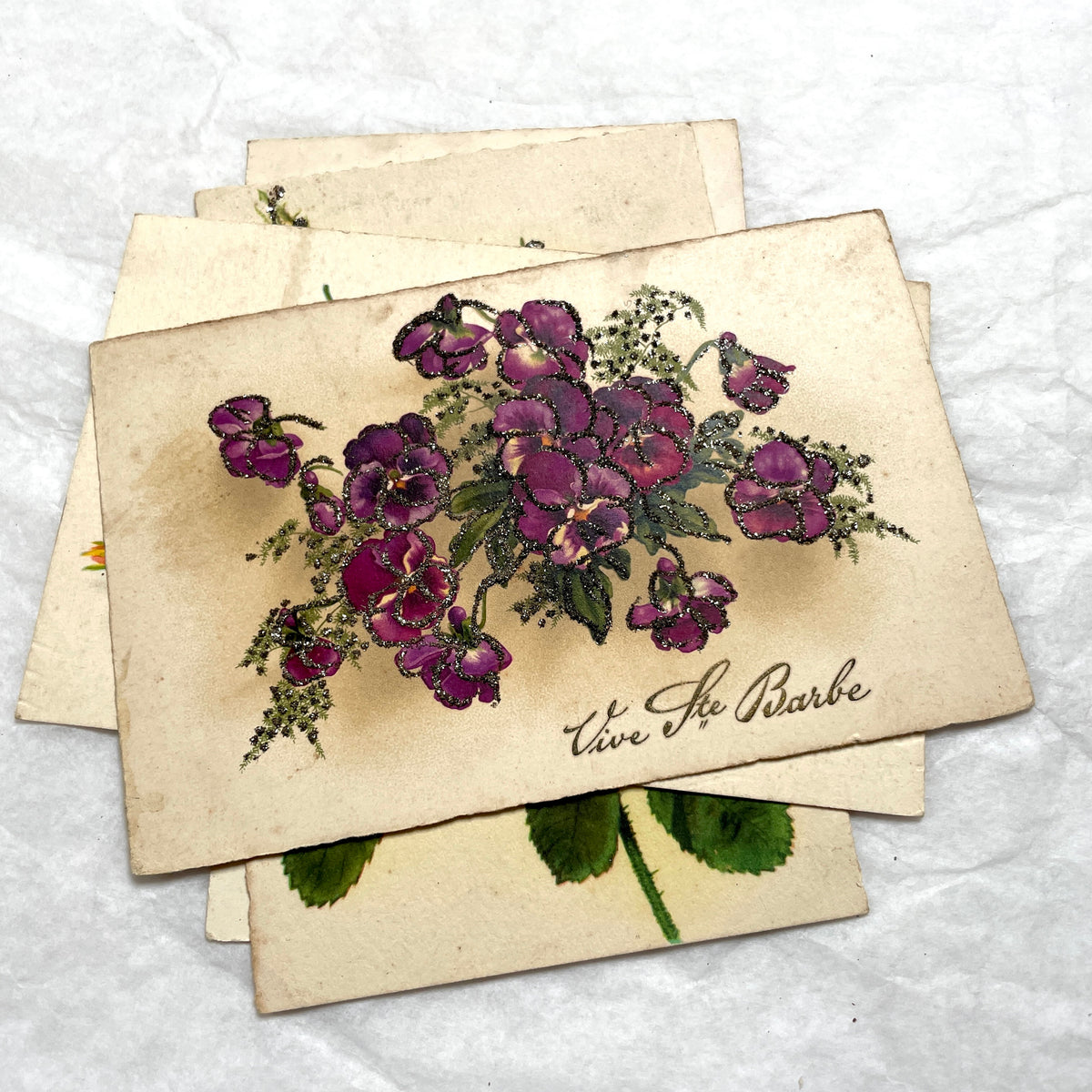 1910s French glitter postcard lot with purple pansies, pink roses, and red rose bouquets.