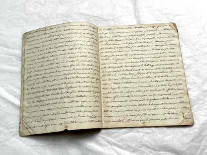 Late 19th Century handwritten French manuscript book with aged pages open to reveal flowing script.