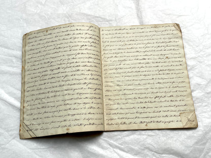Late 19th Century handwritten French manuscript book with aged pages open to reveal flowing script.